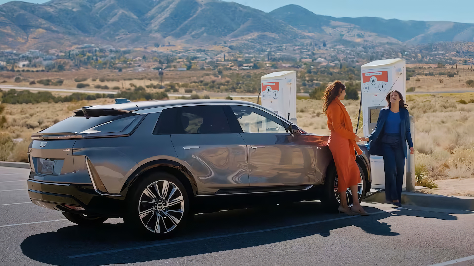 Two EV owners are charging their EVs using a highway-side EV charging post.