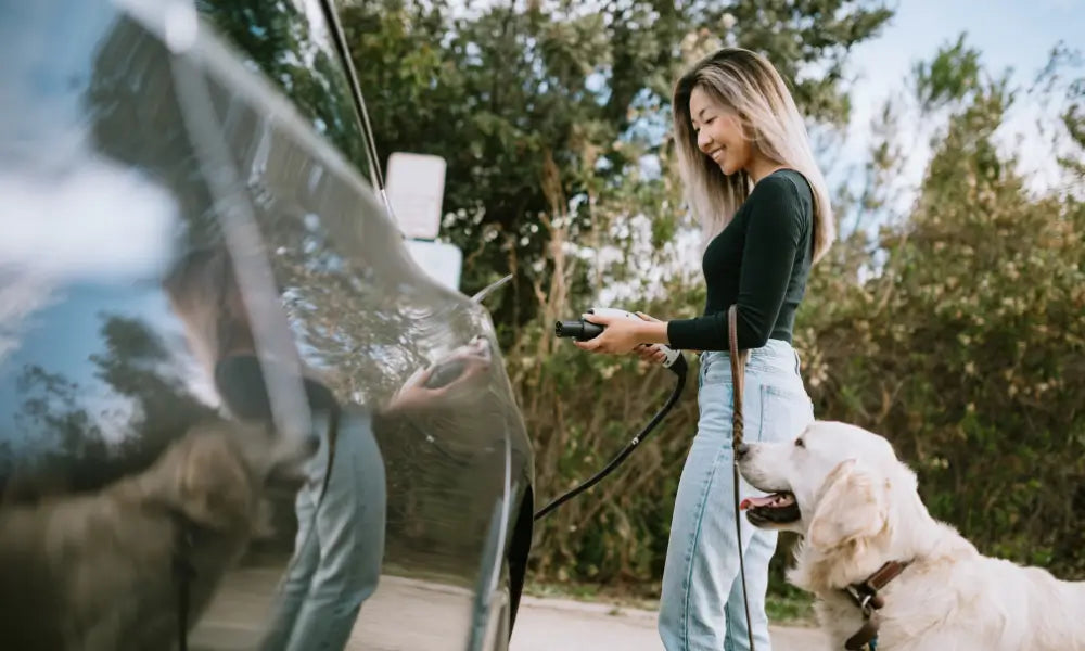 A woman is charging his EV, with her dog beside her.