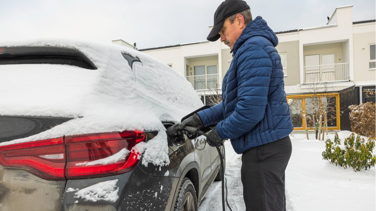 A man using NEMA 14-30 EV charger to charge his EV in snow.