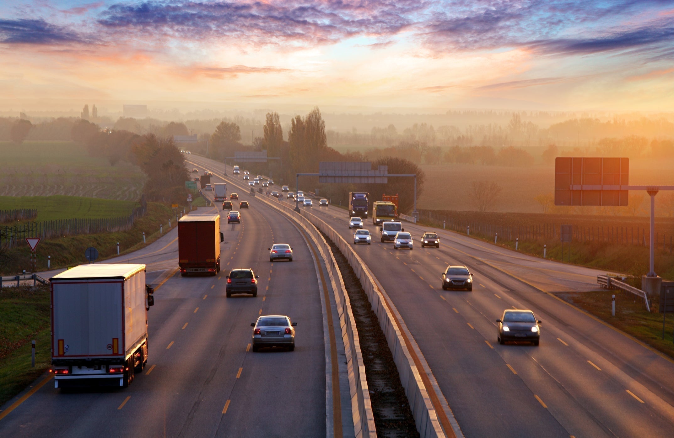 Highway with cars and trucks at sunset with scenic landscape.
