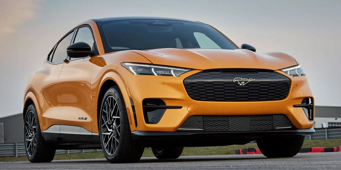 Orange Ford Mach-e driving on the road.