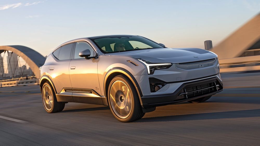 Silver SUV speeding on a bridge with city skyline in the distance.