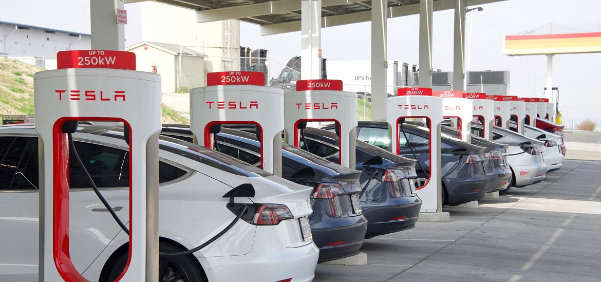Multiple Tesla EVs charging at 250kW stations under canopy.