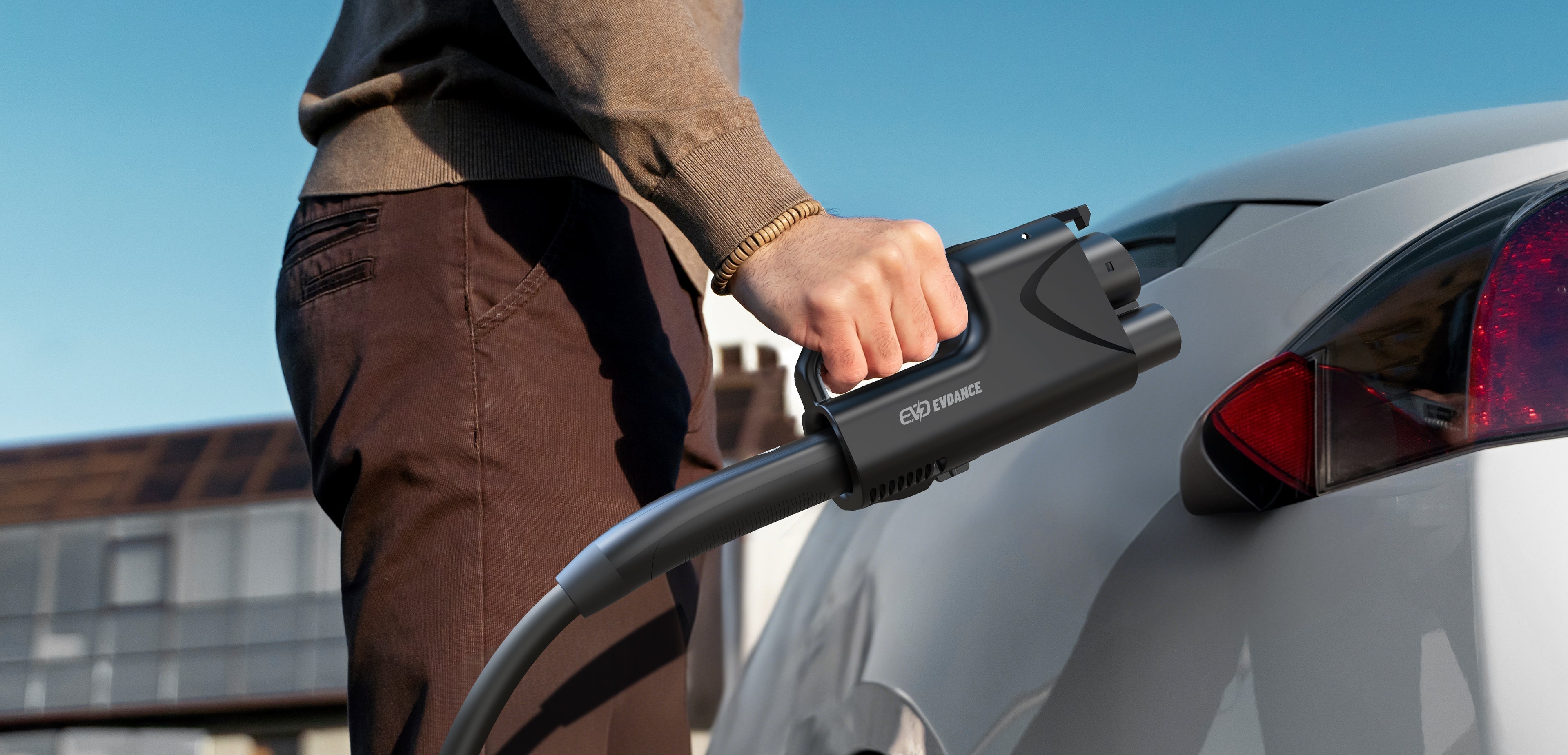 CCS connector image| Person holding an EV charging connector next to a plugged-in electric car in a residential setting| Arabwheels blogs
