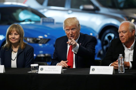 President Trump speaking at table with two officials, EVs in background.