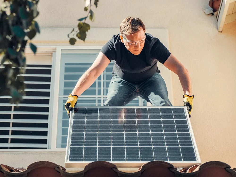 A male installing solar panels on a house