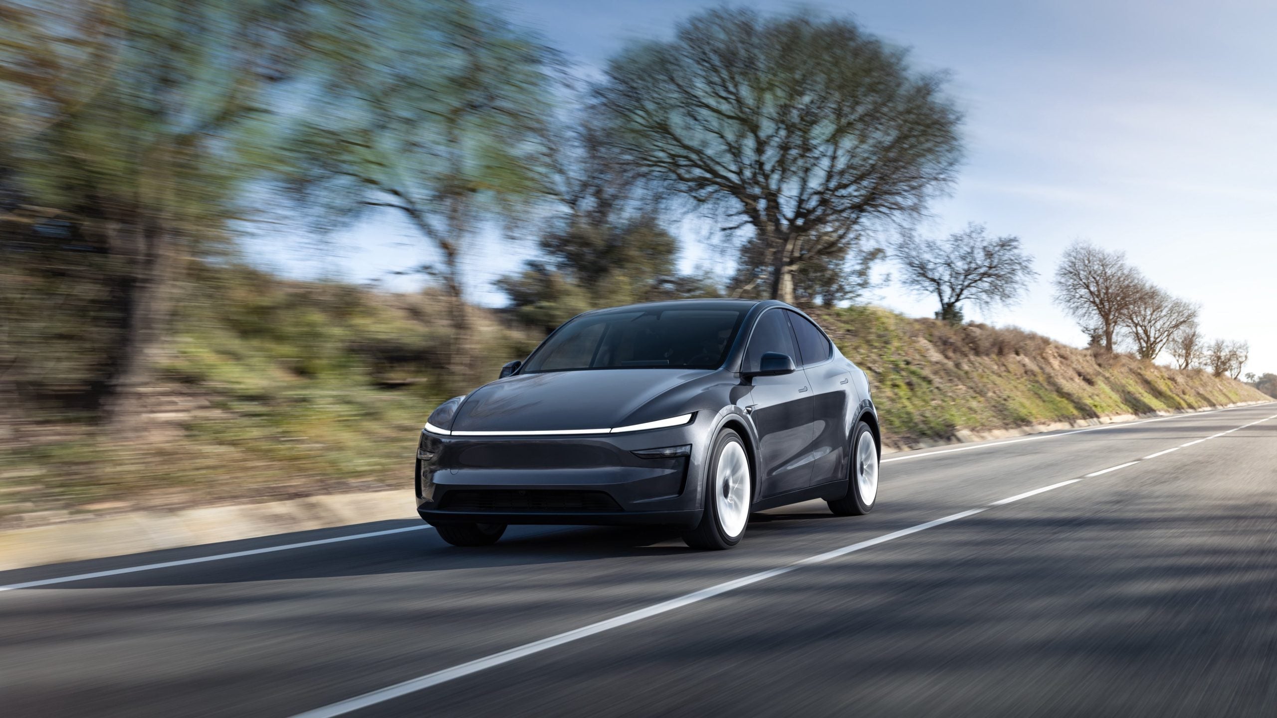 Black upgraded tesla model y driving on the road.